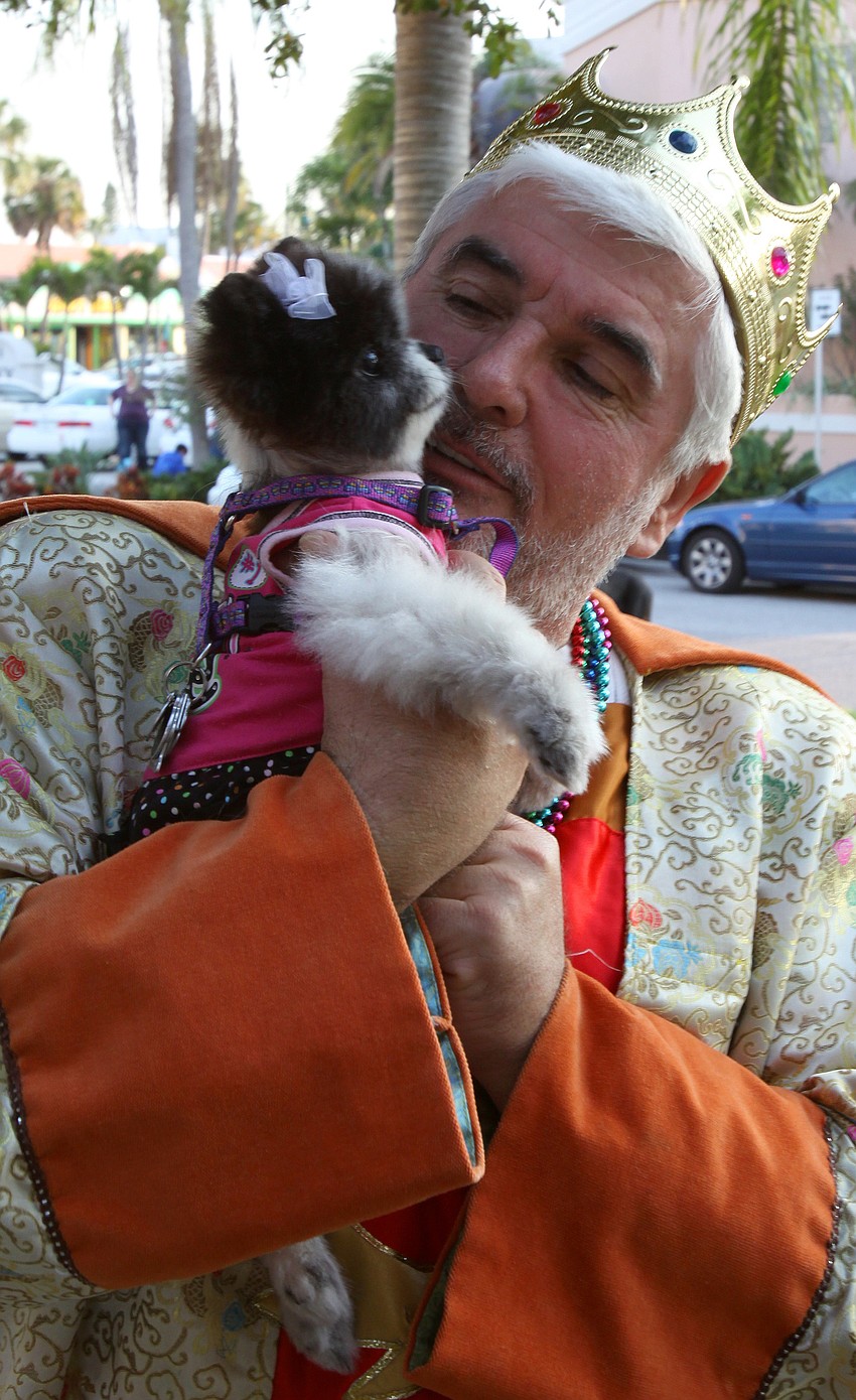 King of Mardi Gras, Cliff Roles, holds up Annabelle, a 5-year-old and 5 lbs. pomeranian, on Tuesday, Mar. 8 during Masquerade â€” Mardi Gras St. Armands Style.
