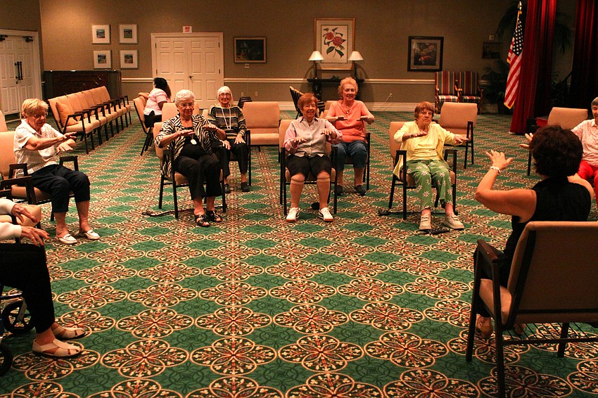 The chair dancers move their hands out and back for one of their exercise motions.