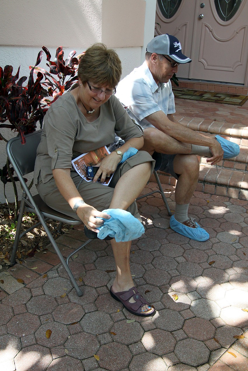 Denise and Bob Reynolds put on the blue booties provided outside each of the homes on the Home and Garden tour.