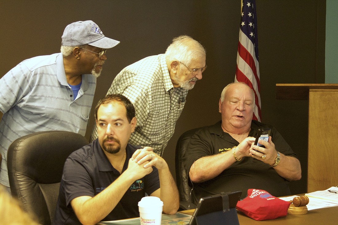 Lewis McCarthy and Jack Carall look on as Mayor Jon Netts shows off some photos of his wounded leg, which required surgery and kept him away from official duties for some time. Netts presided over the July 28 City Council meeting. Photo by Brian McMillan