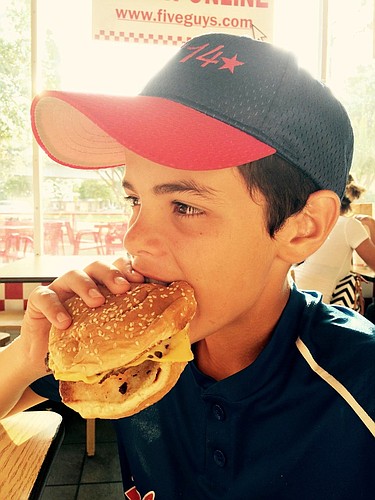 Alex Machado takes a bite out of a chicken sandwich. Photo by Christina Machado