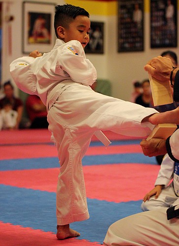 Aden Nguyen kicks through a board to cap off his belt testing. Photos by Jeff Dawsey