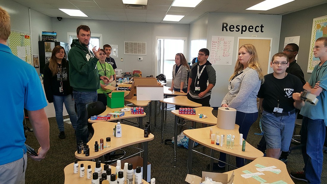 Blake VandeBunte (green sweatshirt), a  social studies teacher at the i3 Academy, talks to his students about homelessness as they prepare to fill boxes with toiletry items. Courtesy photo