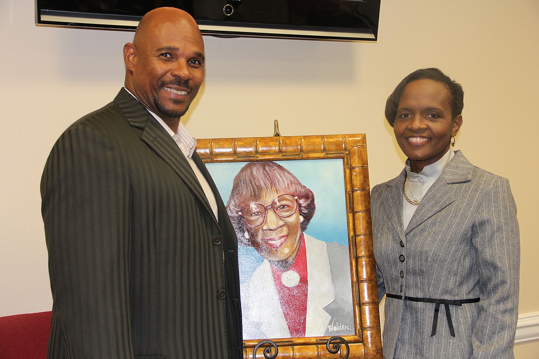 Charles Bethune and Marya Bosley stand by a painting of Shirley Chisholm at a birthday celebration on Monday, Nov. 30. Photo Jacque Estes