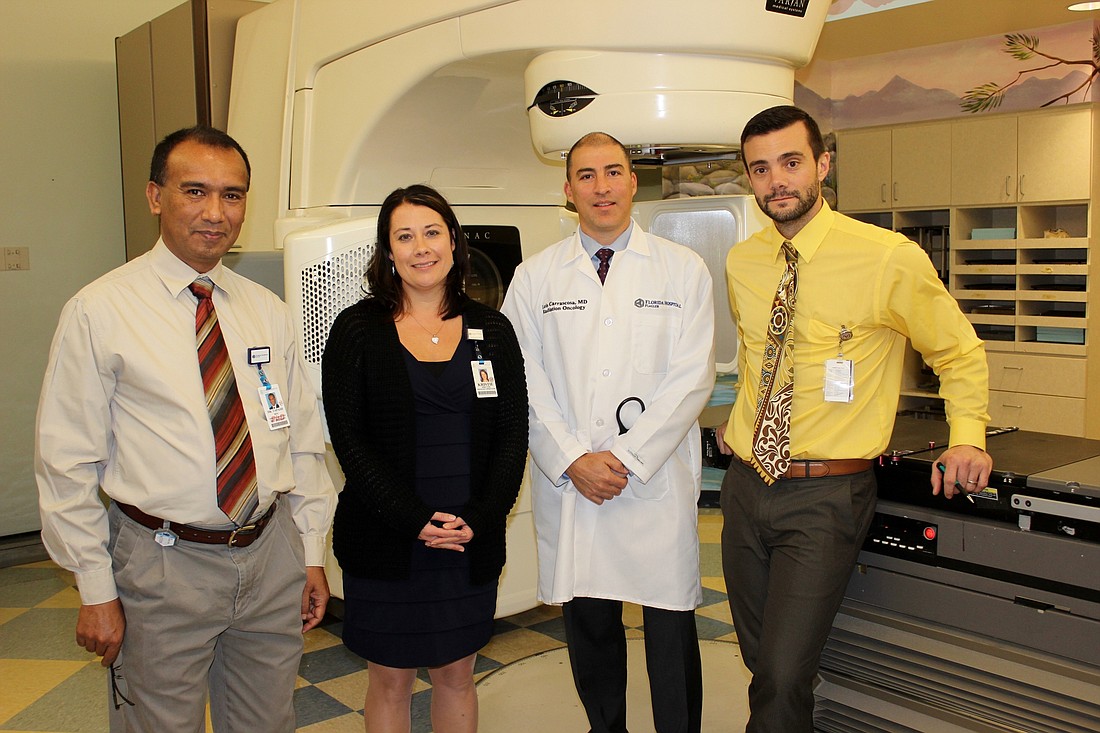 Physicists Tapash Roy (L) and John Dorr (R) stand with Florida Hospital Flagler Director of Oncology Operations Kristie Reiner and Radiation Oncologist Dr. Luis Carrascosa in front of the hospital's linear accelerator. Photo by Jeff Dawsey