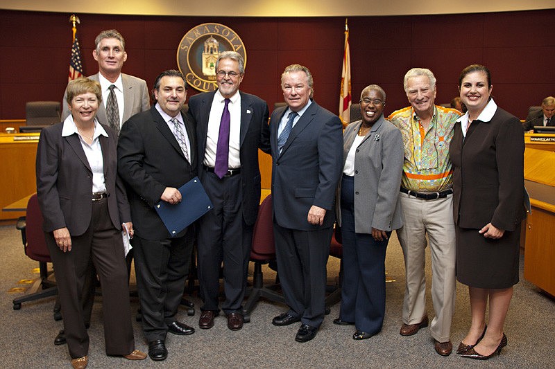 County commissioners surround Michael's On East co-proprietors Phil Mancini, third from left, and Michael Klauber, fifth from left. Photo courtesy of Sarah Lansky.