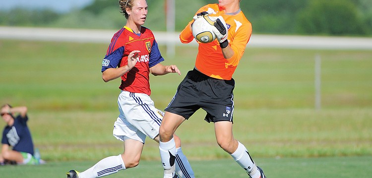 IMG Soccer Academy goalkeeper Mike Mitchell saves a shot by RSL Florida's Jake Frahm.