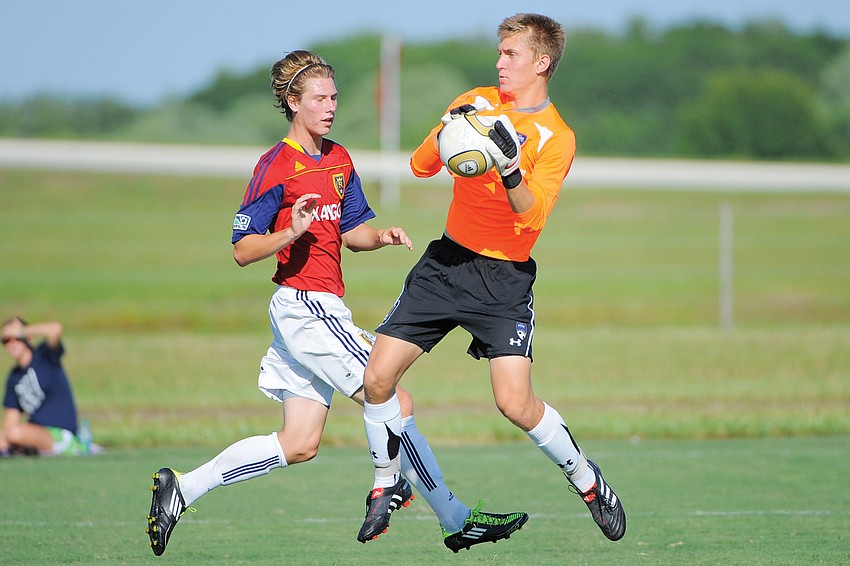 IMG Soccer Academy goalkeeper Mike Mitchell saves a shot by RSL Florida's Jake Frahm.