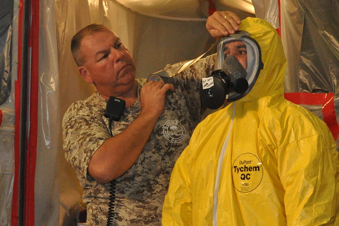 Palm Coast Fire Department Lt. Randy Holmes helps firefighter Joey Paci don a chemical protective suit in a presentation for reporters Nov. 13.