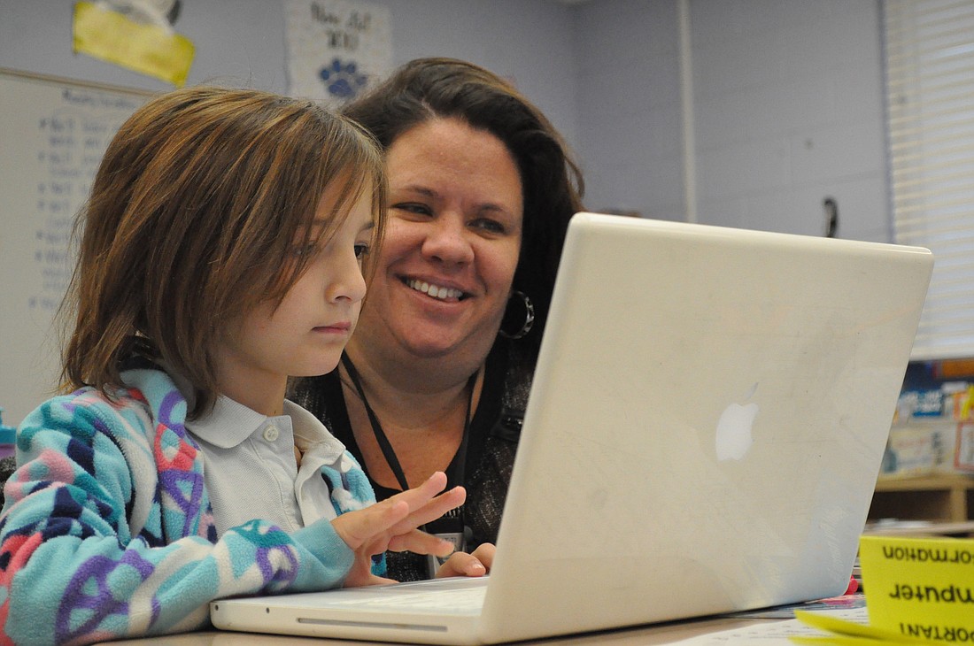 Belle Terre Elementary School teacher Agatha Lee and helps second-grader Grace Reilly with a coding problem.