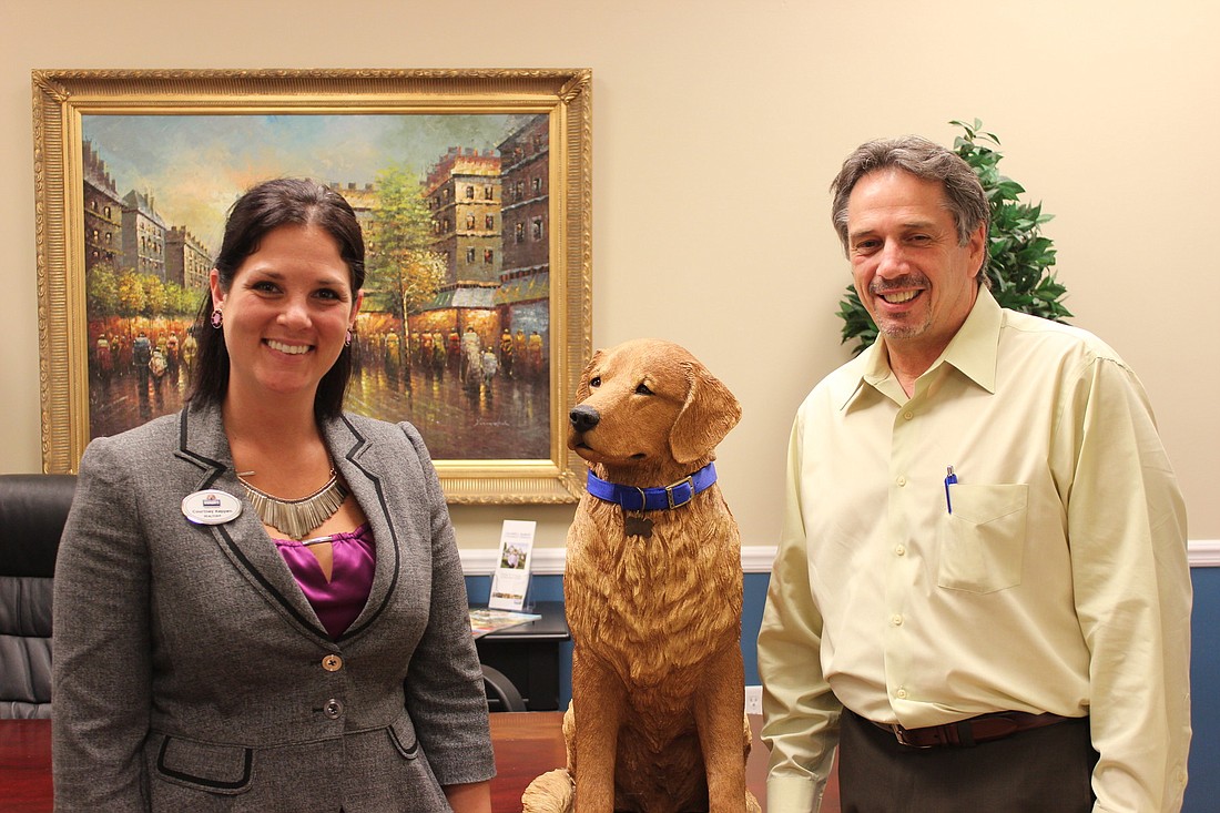 Coldwell Banker employees, Courtney Keppen and Tom Heiser, share a moment with the companyÃ¢â‚¬â„¢s mascot, Russell the Golden Retriever.
