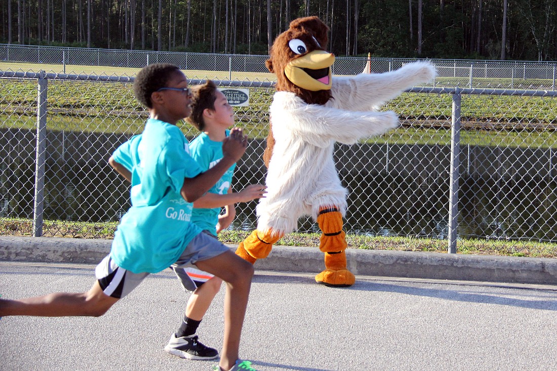 The Rymfire Elementary School Roadrunner directs the first two 5K finishers, Timothy King and Landon Gonzalez, to the finish line.