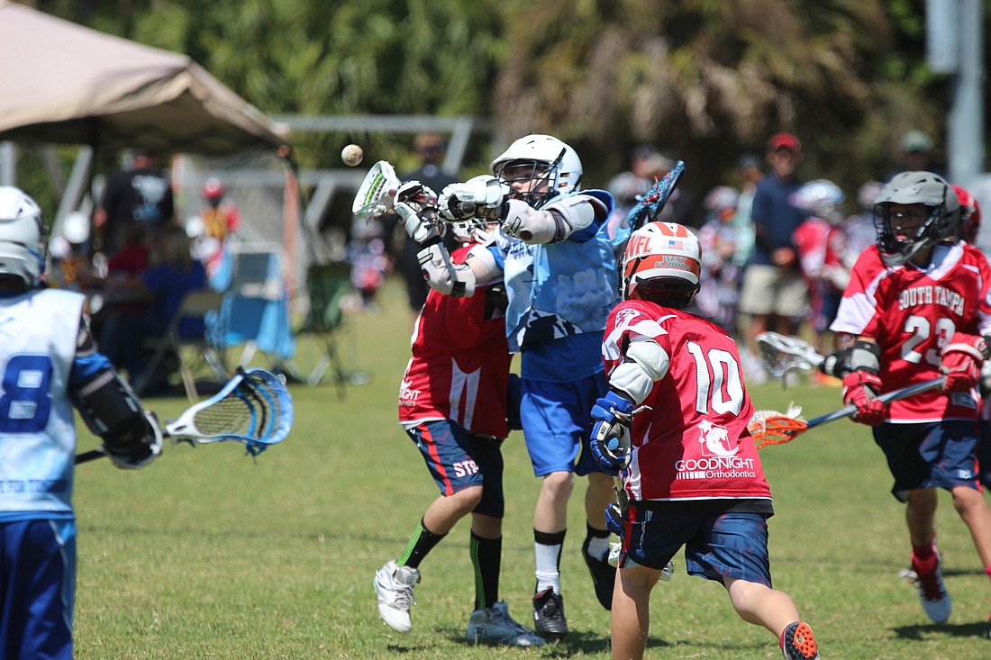 Keegan Shults takes a shot between two defenders for Blue Skies Lacrosse 11U team.