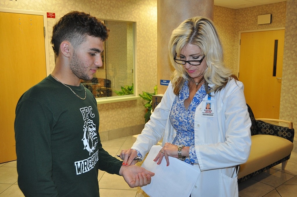 Denise Duty, Florida Hospital Flagler director of inpatient nursing, records FPC wrestler Michael DeAugustinoÃ¢‚¬„¢s pulse during the hospitalÃ¢‚¬„¢s annual free sports physical event.