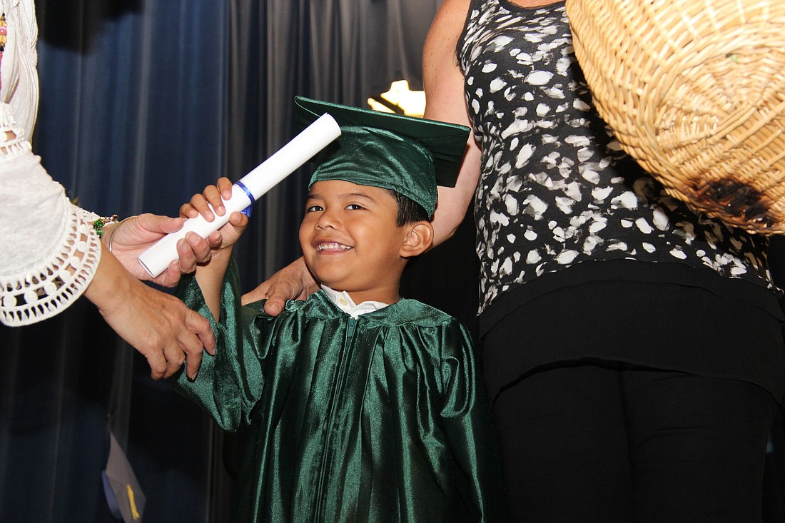 Alfonso Oliver-De Jesus accepts his diploma from his teacher, Mercy Delgado.