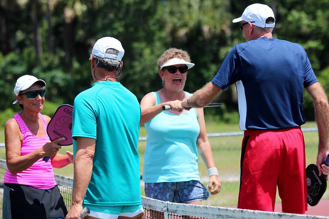 Teammates Ken and Sandy LaPrall, and Steve and Jeanne Mager, fist-bump after a close game.