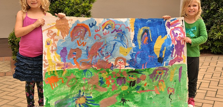 Kennedy McClain and Piper Carson hold the preschool's mural.