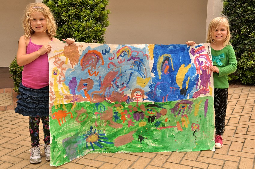 Kennedy McClain and Piper Carson hold the preschool's mural.