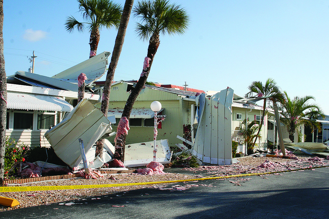 Pieces of a metal roof and pink insulation litter a street in the Twin Shores mobile-home park after a powerful gust of wind and rain damaged the area Thursday, March 31.