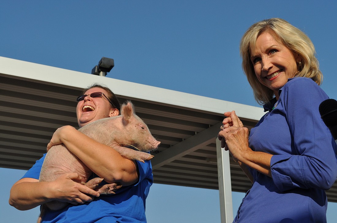 Gullett Elementary Principal Kathy Hayes, right, grins after smooching a 10-week-old pig for the students.