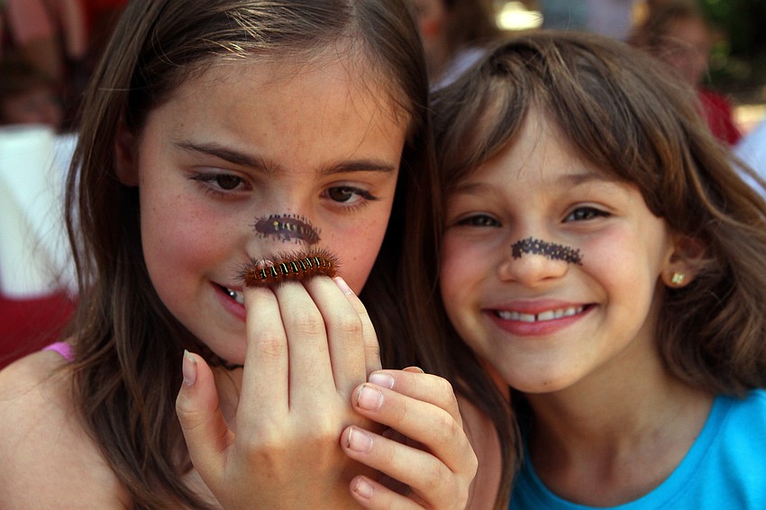 Trinity Redhead and Arianne Shedlock, 8, hold up the caterpillar they found during the Earth Day Celebration. The girls also had caterpillars painted across their noses and named their new friend 