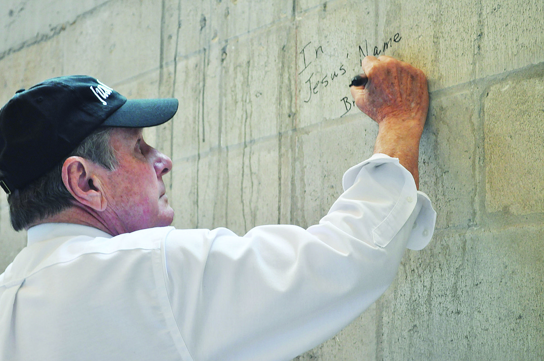The Rev. Bruce Porter signs the wall in the sanctuary.