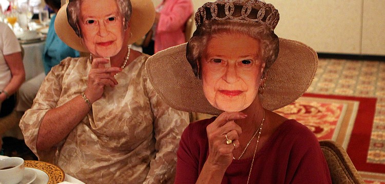 Angela Ward and Holly Kraft wear Queen Elizabeth cardboard masks Friday, April 29 while celebrating the royal wedding at the Ritz Carlton.