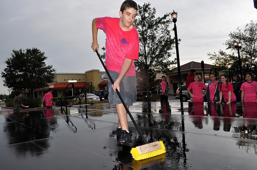 Eighth-grader Michael Miller clears water off of the stage as his fellow orchestra members look on.