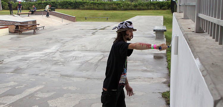 Jacob Hill of Consolidated Consciousness primes the wall that will be covered in graffiti art by Tion Bukue during the Golden Era Tour event at Payne Park's skate park.