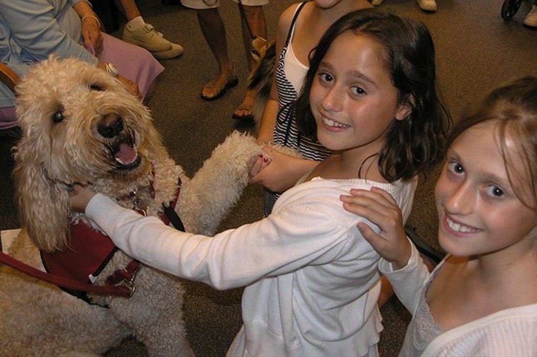 East County sisters Audrey and Abby Lipton greet a pet therapy dog during a nursing home visit.