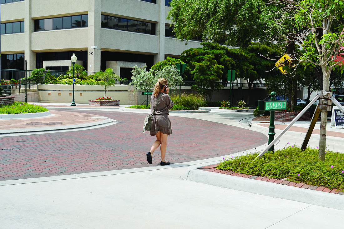 A woman walks on the perimeter of the Five Points roundabout between Selby Five Points Park and First Watch restaurant. Planters will be placed on the corner of the roundabout at First Watch to guide pedestrians to the proper crosswalk.