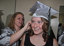 Breanna Howell, behind, helps Emily Wray pin on her cap.