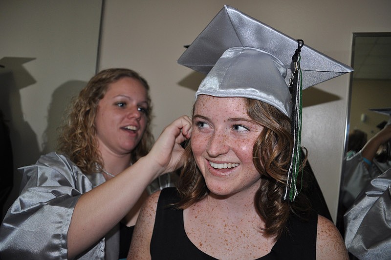Breanna Howell, behind, helps Emily Wray pin on her cap.