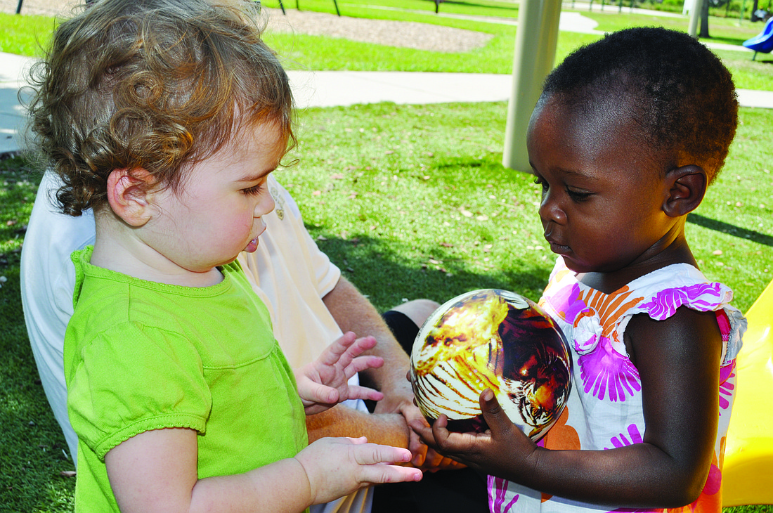 Juliet Ferguson plays with her adopted sister, Mercy, during the celebration for Ugandan children and their adoptive families June 4 at Greenbrook Adventure Park.