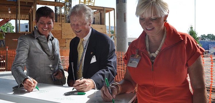 SMH CEO Gwen MacKenzie, Board Chairman Robert Strasser and Healthcare Foundation CEO Alex Quarles sign the last beam to be hoisted as a gesture of good luck.