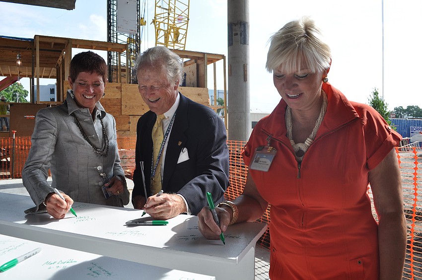 SMH CEO Gwen MacKenzie, Board Chairman Robert Strasser and Healthcare Foundation CEO Alex Quarles sign the last beam to be hoisted as a gesture of good luck.