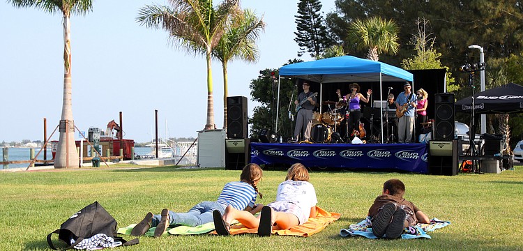 Three kids sprawl out on towels and watch Soul R Coaster perform during the Sarasota Yacht Club's 1st ever Concert on the Lawn event Saturday, June 11 at the Sarasota Yacht Club.