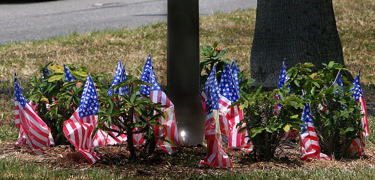 A dozen or so American flags set up around the base of the sign denoting the Blue Star Memorial Highway flap in the breeze on Flag Day, Tuesday, June 14.
