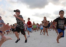 Some of the over 300 participants leave the starting line in a frenzy during the 1-mile fun run Tuesday, June 14 on Siesta Key Beach.