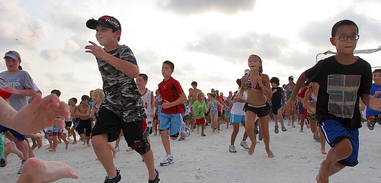 Some of the over 300 participants leave the starting line in a frenzy during the 1-mile fun run Tuesday, June 14 on Siesta Key Beach.