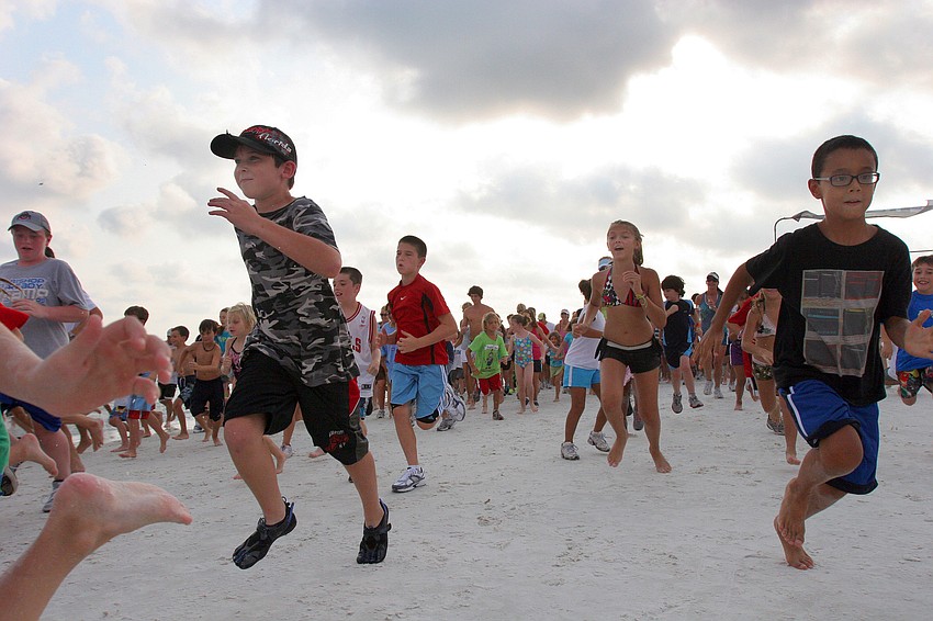 Some of the over 300 participants leave the starting line in a frenzy during the 1-mile fun run Tuesday, June 14 on Siesta Key Beach.
