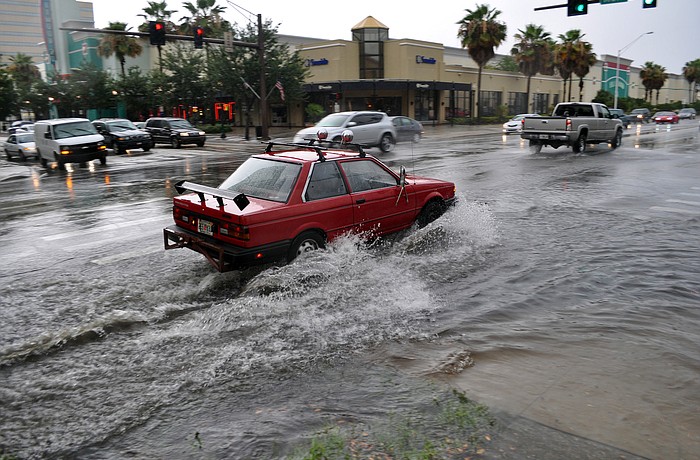 This red car has a difficult time making it through the flooded intersection downtown after an afternoon storm.