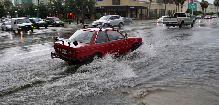 This red car has a difficult time making it through the flooded intersection downtown after an afternoon storm.