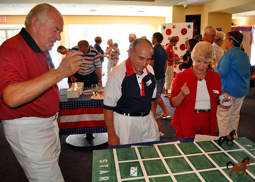 Marty Cooper plays a horse racing game with Bill and Judy Stanford Monday, July 4 at Bird Key Yacht Club.