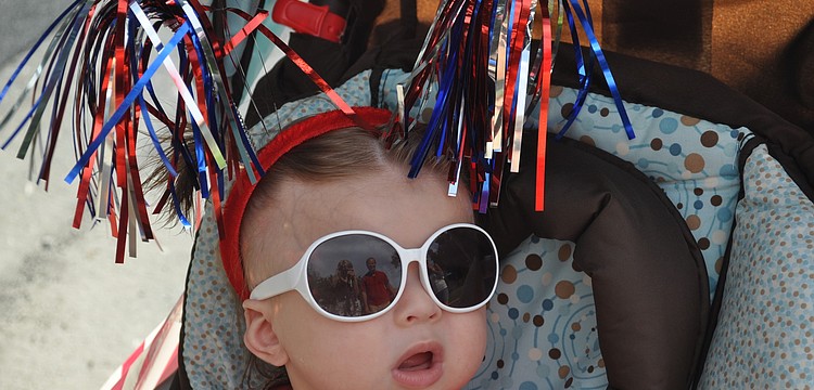 Mia Gubernat rides through the Freedom Fest parade wearing red-white- and-blue pom-poms.
