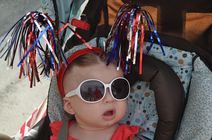Mia Gubernat rides through the Freedom Fest parade wearing red-white- and-blue pom-poms.
