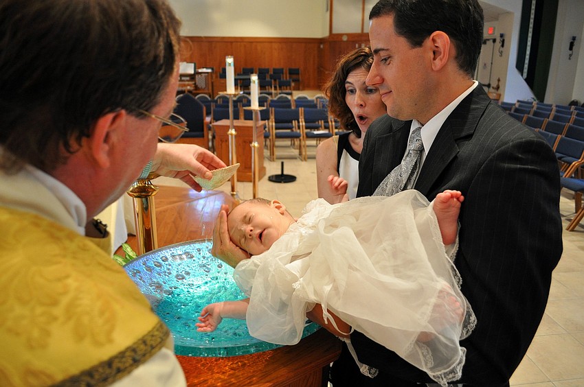 Lori Wolcott gasps as Fr. Dan dumps the first bit of holy water onto her son, Colin Spencer, 6 mos., during his Baptism Saturday, June 18 at Our Lady of the Angels.