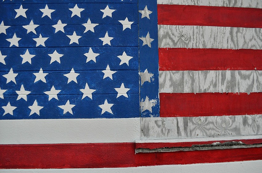 The building for the Honorably Discharged Veterans of Sarasota has a large American flag painted on one side of the building where there is a boarded up window. The building hosts meetings for veterans and holds bingo on Saturday nights.Â