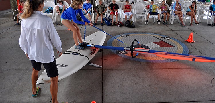 Laurel Kaiser steadies the simulator while Elizabeth Kamm, 9, starts to bring up her sail Friday, July 8 during the Island Style Water Sports Camp.