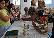Charlotte Smith shows the class how to blow through the straw lightly in order to make the paint look like tree limbs Friday, July 8 at the Art and Photography Studio of Colleen Cassidy.